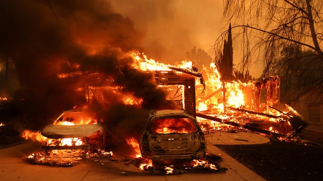 Vehicles and a house burn as powerful winds fueling devastating wildfires in the Los Angeles area force people to evacuate, at the Eaton Fire in Altadena, California, Jan. 8, 2025. 