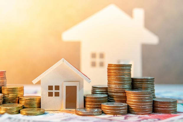 Real estate or property investment. Home mortgage loan rate. Saving money for retirement concept. Coin stack on international banknotes with house model on table. Business growth background 