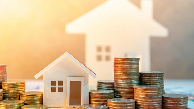 Real estate or property investment. Home mortgage loan rate. Saving money for retirement concept. Coin stack on international banknotes with house model on table. Business growth background 