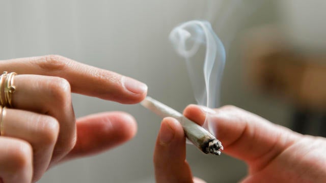 Hands of man and woman passing marijuana joint 