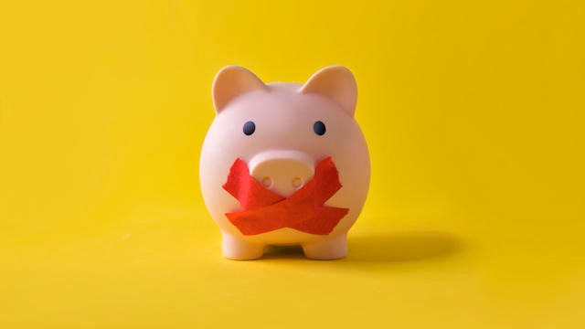 Piggy bank with a cross covering it's mouth. 