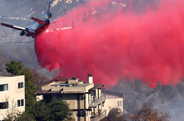 Firefighting aircraft drops pink flame retardant over a neighborhood in Los Angeles
