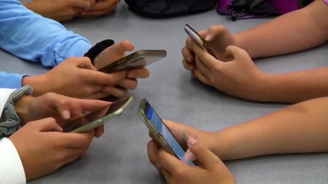 Children's hands are seen holding cellphones